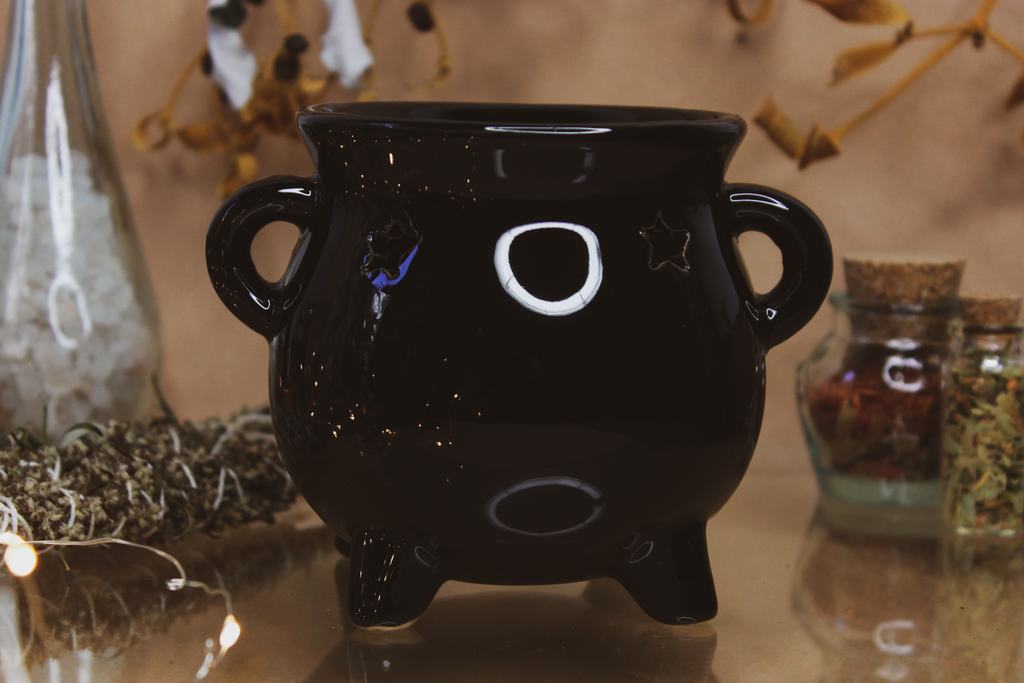 Eine schwarze Keramik-Duftlampe in Form eines Hexenkessels.