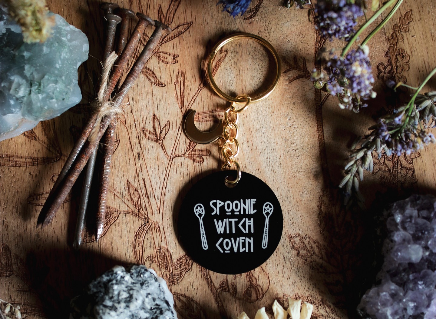 Ein Schlüsselanhänger in Schwarz und Gold mit goldenem Mond-Charm. Auf der schwarzen Scheibe steht in weiß: Spoonie Witch Coven.