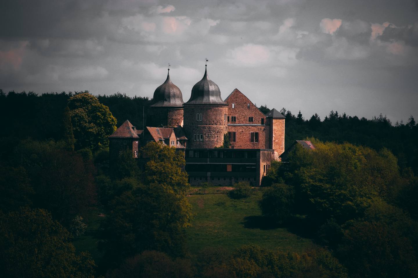 Panorama-Aufnahme der Sababurg. Zu sehen ist gesamte Burg mit ihren Türmen und der Waldlandschaft drumherum.